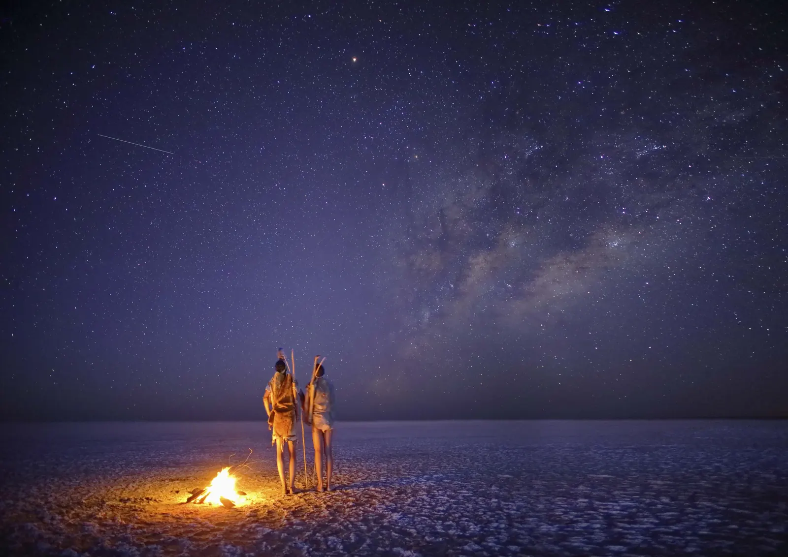 Travellers stargazing beside a campfire in Botswana