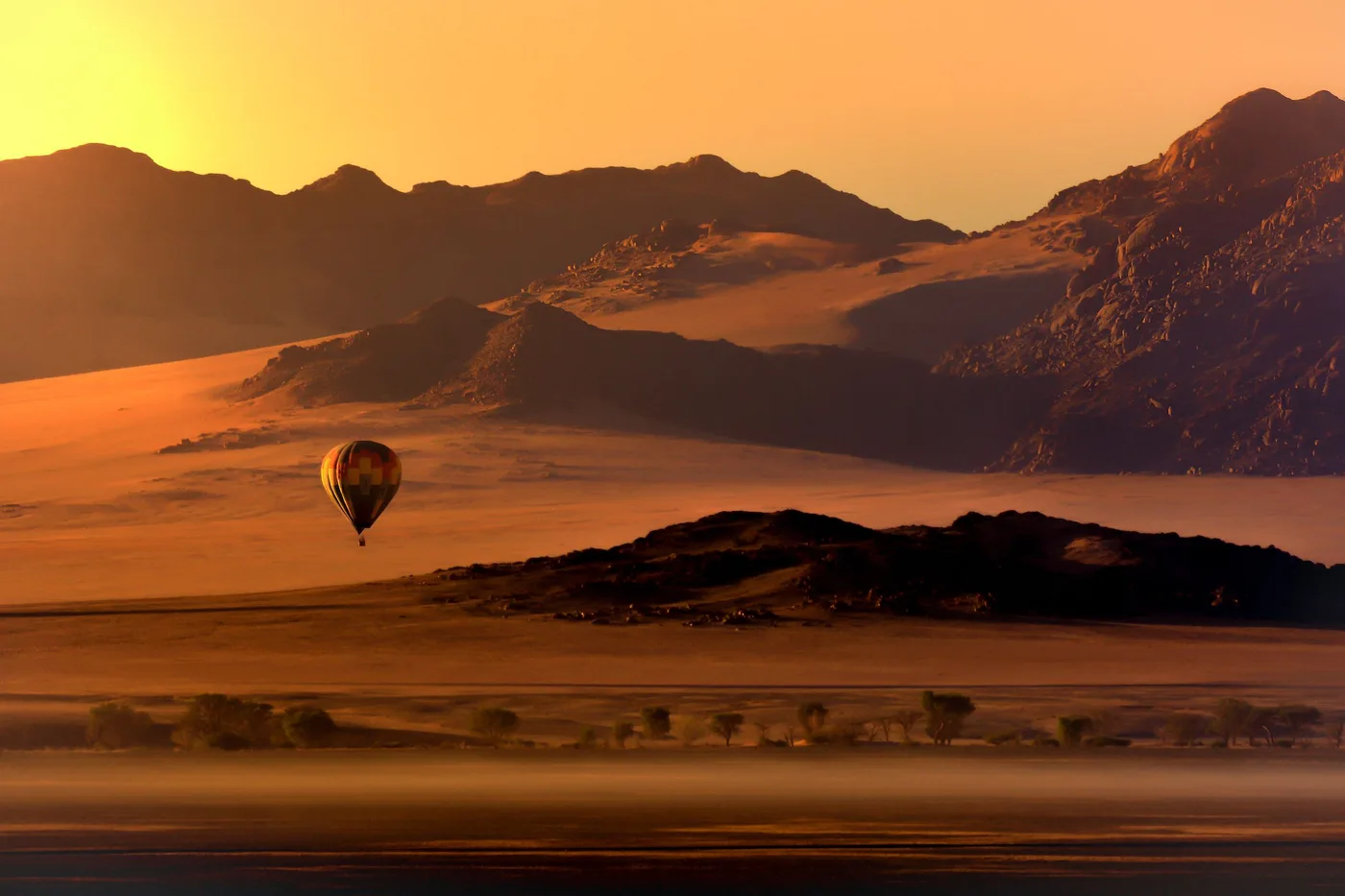 Hot-air balloon rising over Namibian dunes